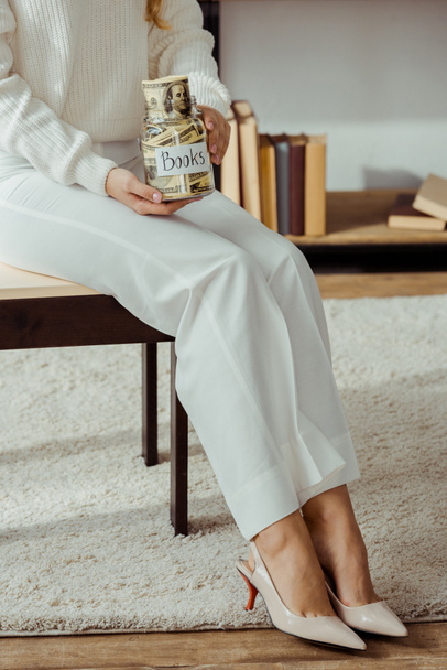 gros plan de femme tenant un bocal en verre avec des économies d'argent et des livres
  - Photo, image