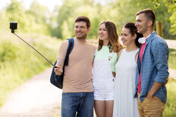 friends take picture by smartphone on selfie stick - Фото, изображение