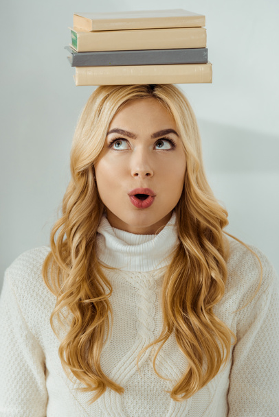 close up of adult woman with funny face expression and books on head  - Photo, Image