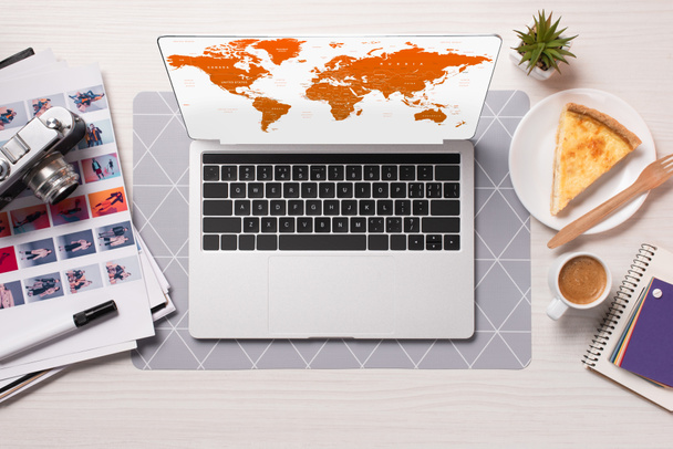 office desk with laptop with world map on screen, flat lay - Photo, Image