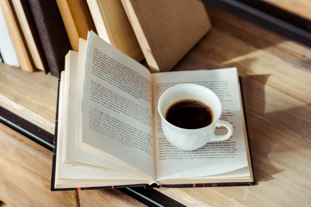 primer plano del libro abierto con una taza de café en la estantería
 - Foto, Imagen