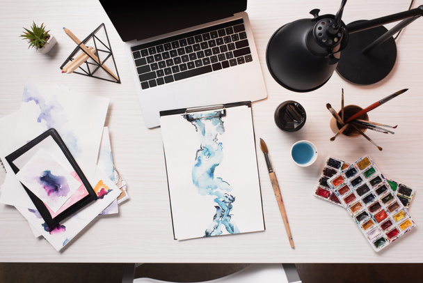 офисный стол с ноутбуком, эскизы и художественные принадлежности, плоский уголок
 - Фото, изображение