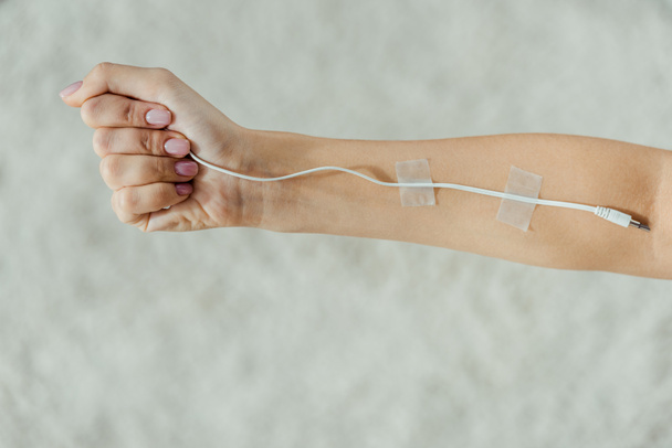 close up of female hand with attached white cable like medical IV infusion, music concept  - Photo, Image
