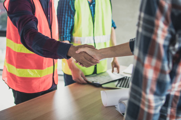 ingeniero y trabajador se dan la mano antes de cepillar y hablar edificio de construcción
. - Foto, imagen