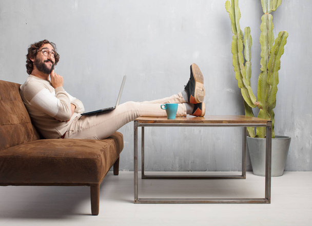 young bearded man sitting on a leather sofa in a vintage living room - Foto, imagen