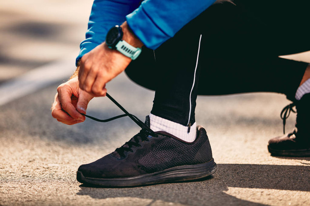 Close up of man tying shoelace on sneakers. City life, sportswea - Фото, зображення