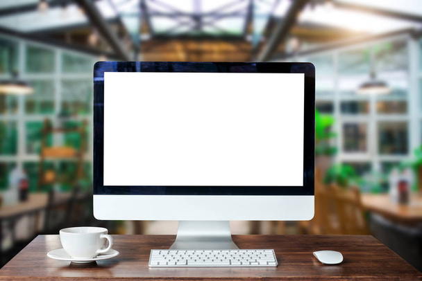 Monitor de computadora, teclado, teléfono inteligente de taza de café, tableta y ratón con pantalla en blanco o en blanco aislado está en la mesa de trabajo en el coffeeshop  - Foto, Imagen