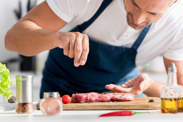close up of handsome man salting steak on cutting board - Photo, Image