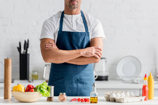 hombre en delantal de pie en la cocina con los brazos cruzados
 - Foto, Imagen