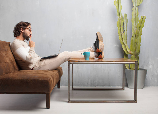 young bearded man sitting on a leather sofa in a vintage living room - Foto, Bild