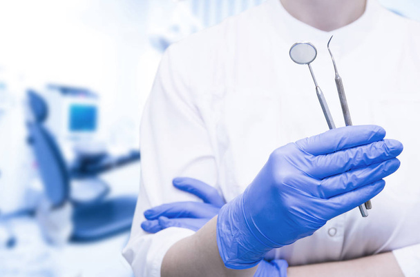 Стоматолог в перчатках держит стоматологические инструменты в стоматологической клинике
 - Фото, изображение
