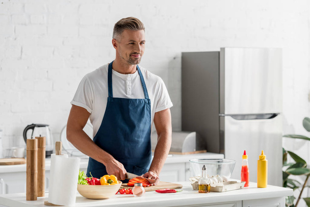 hombre adulto de pie en la cocina y hacer ensalada
 - Foto, Imagen
