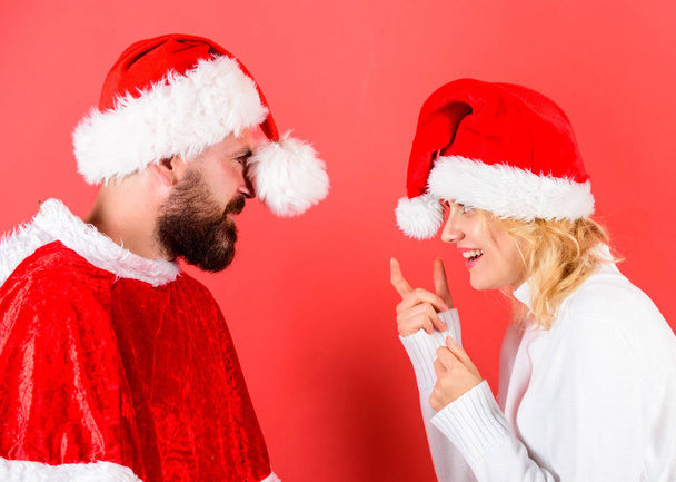 Man with beard and woman santa hat red background. Rent santa costume. Couple celebrate winter holiday christmas party. Christmas masquerade karnival concept. Couple cheerful face celebrate christmas - Photo, Image