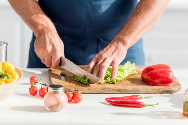 partial view of man cutting lettuce on chopping board for salad - Foto, Imagem