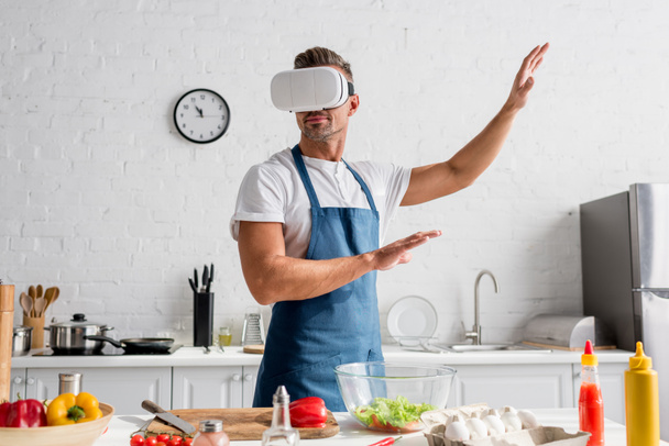 man in virtual reality headset gesturing at kitchen - Foto, afbeelding
