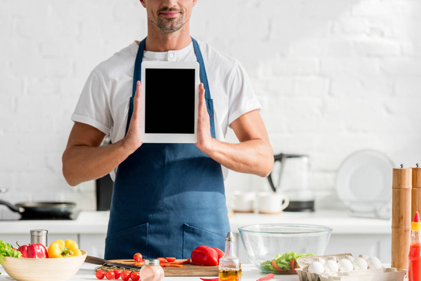 man in apron with digital tablet in hands at kitchen - 写真・画像