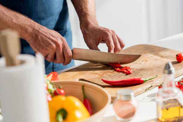 zár-megjelöl kilátás-a férfi kezét vágás chili paprika a vágódeszka - Fotó, kép