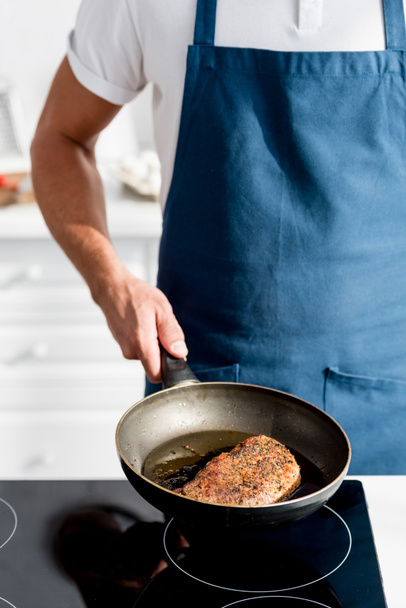 partial view of man holding pan with cooked steak - Foto, afbeelding