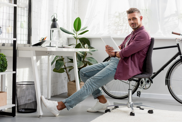  relaxing man sitting on chair with digital tablet at home office - Photo, Image