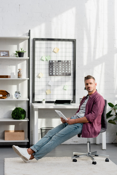 uomo adulto seduto sulla sedia con tablet digitale a casa ufficio
 - Foto, immagini