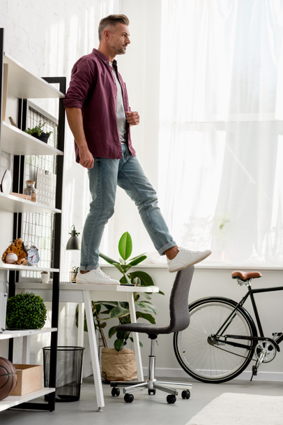 man stepping off table at home office - 写真・画像