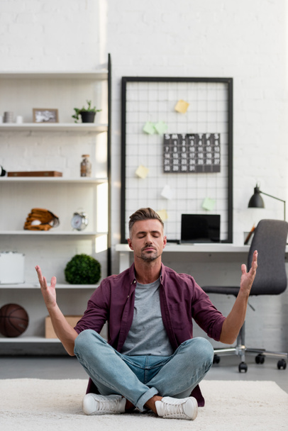 hombre sentado en el suelo y practicando yoga en casa oficina
 - Foto, Imagen