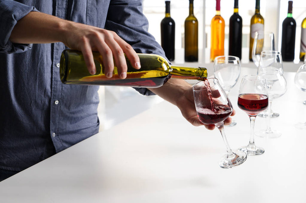Μπάρμαν έκχυση γευστικό κρασί σε ποτήρι σε πάρτι - Φωτογραφία, εικόνα