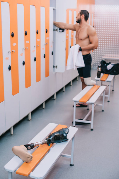 athletischer junger Sportler mit Beinprothese in der Umkleidekabine des Schwimmbades - Foto, Bild