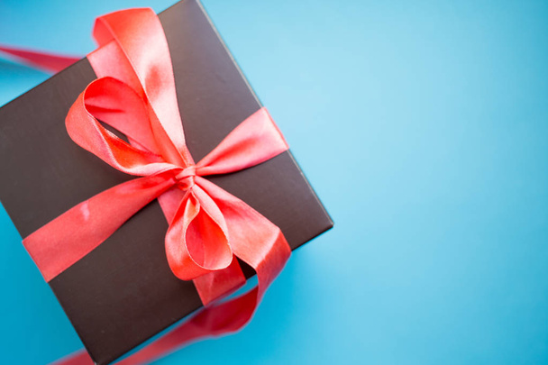 Brown gift box with red ribbon on blue background. copy space. - Fotó, kép