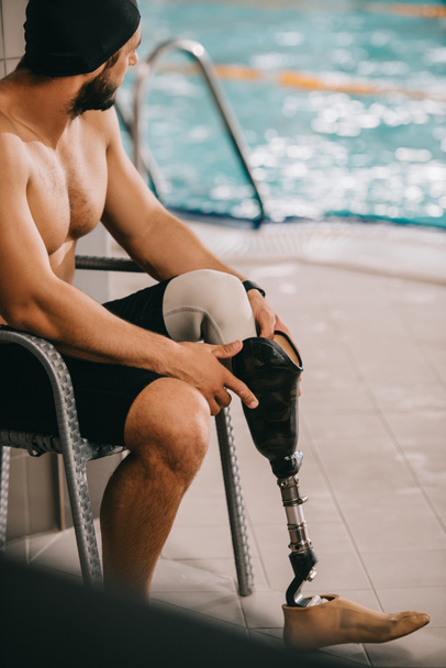 deportista feliz con pierna artificial sentado en la silla en la piscina cubierta
 - Foto, Imagen