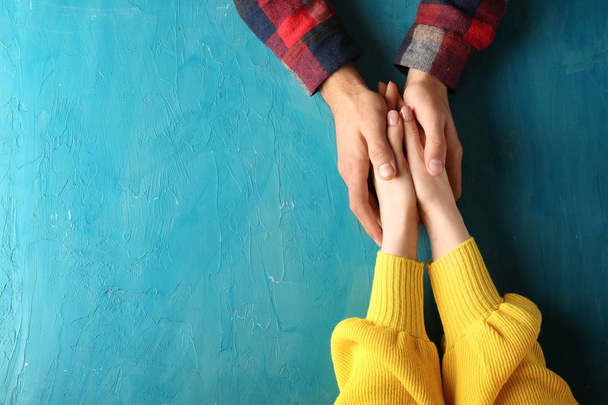 Loving young couple holding hands on color background - Fotografie, Obrázek