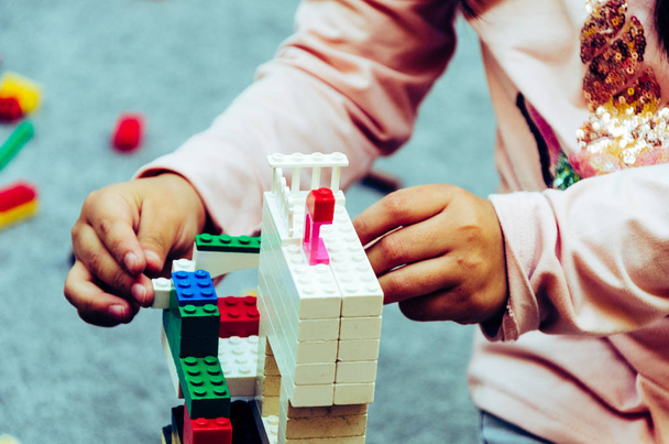 Κοριτσάκι παίζει με πολύχρωμα τουβλάκια στο σπίτι ή στον παιδικό σταθμό - Φωτογραφία, εικόνα
