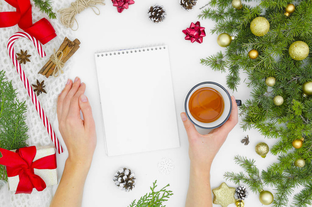 Kerst Mock up spiraal notebook, blanco vel wit papier. Bovenaanzicht van dames handen houdt thee. Creativiteit mockup van takken en Kerst decoraties winter Nieuwjaar en Kerstmis. Plat leggen - Foto, afbeelding