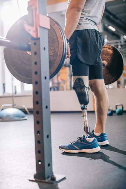 cropped shot of man with artificial leg working out with barbell at gym - Foto, afbeelding