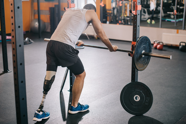 csinos fiatal sportoló mesterséges láb támaszkodva súlyzó-on tornaterem - Fotó, kép