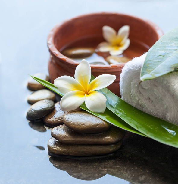Top view of spa stones and flowers for massage treatment on dark background. - Photo, Image