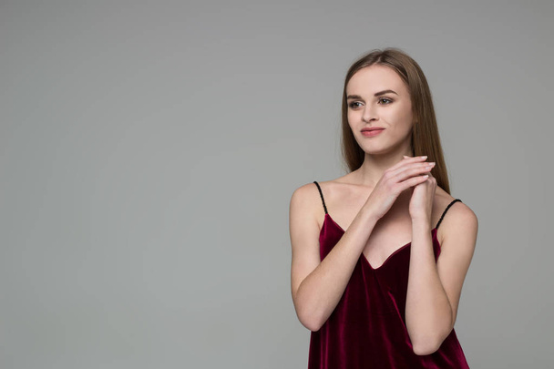 Portrait of posing young model long-haired blond girl in dark red dress showing emotions - Photo, Image