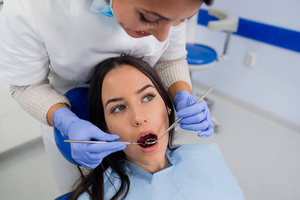 歯科医院で歯の検診。歯医者の女の子の歯を調べること - 写真・画像
