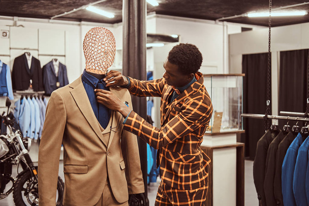 Afro-mężczyzna ubrany w modny elegancki garnitur, praca w sklepie klasycznej odzieży męskiej. - Zdjęcie, obraz