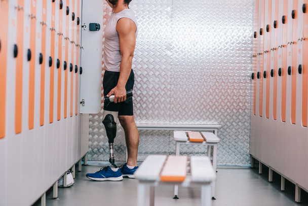cropped shot of sportsman with artificial leg taking stuff from gym locker - 写真・画像