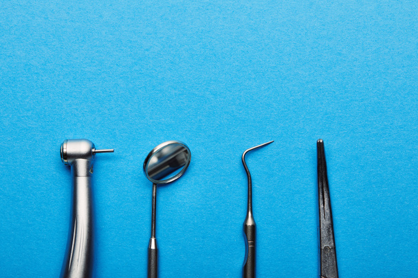 flat lay with arranged stainless dental instruments on blue tabletop, dentistry and dental care concept - 写真・画像