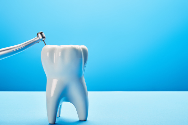 visão de perto da broca dentária e modelo de dente branco no fundo azul, conceito odontológico
 - Foto, Imagem