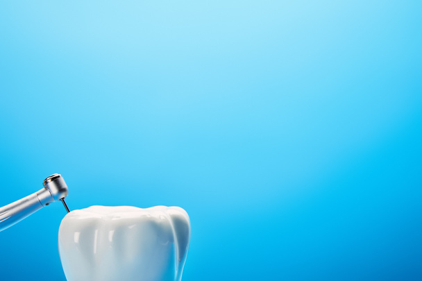 Nahaufnahme des Zahnbohrers und des weißen Zahnmodells auf blauem Hintergrund, Konzept der Zahnmedizin - Foto, Bild