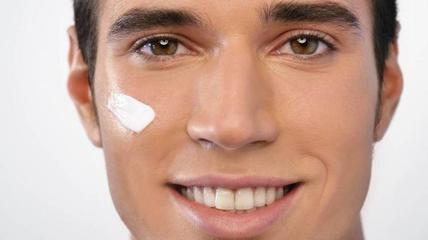 Close up de um homem com hidratante para o rosto sorrindo porque hidrata a pele e protege contra impurezas com efeitos anti-envelhecimento. Conceito de: beleza e cuidados com o corpo, cremes, cuidados com a pele
 - Foto, Imagem