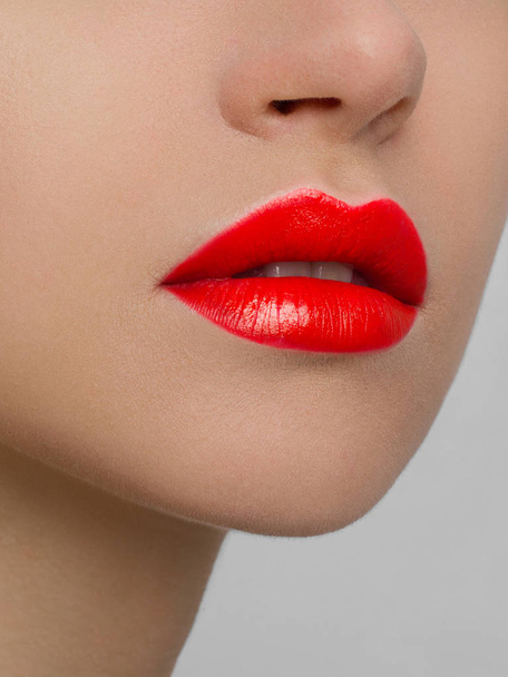 The macro photo of the closed female mouth. Chubby lips with red lipstick show a fashionable make-up and increase in lips. Cosmetology, Spa, cosmetics - Valokuva, kuva