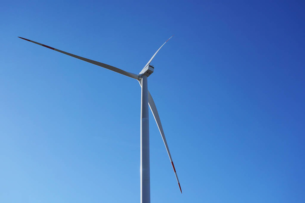 Ekovoimaa, tuuliturbiineja sinisellä taivaalla. vaihtoehtoiseen sähköön tarkoitettu tuulivoimala. Uusiutuva sähkölaitos, jossa käytetään kestävää ympäristöystävällistä teknologiaa ja tuulienergian kiertoa uusiutuviin tuulivoimaloihin
 - Valokuva, kuva
