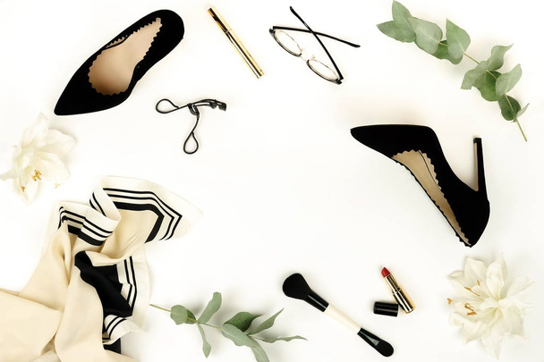 Flat lay, top view female black high heels shoes, accessories and make up cosmetics on a white background. bag, headscarf, glasses, lipstick, mascara, powder, brush, parfume .  Copy space. - Фото, изображение