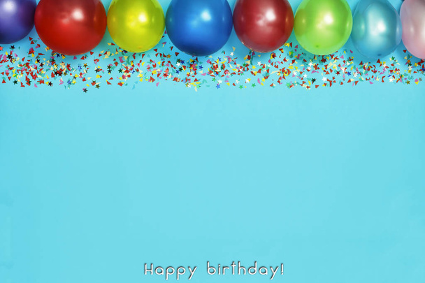 Multicolor party or birthday background on blue with a frame of colorful party balloons, streamers, confetti and candy around central copy space. Happy Birthday  - Photo, Image