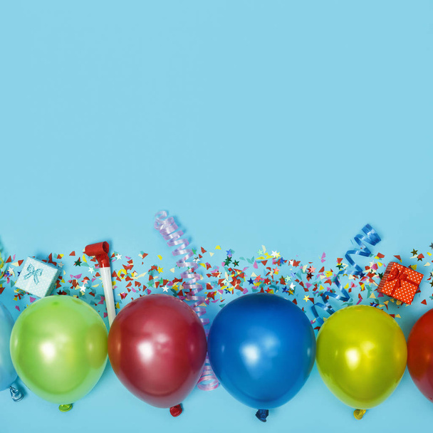 Multicolor party or birthday background on blue with a frame of colorful party balloons, streamers, confetti and candy around central copy space - Photo, Image