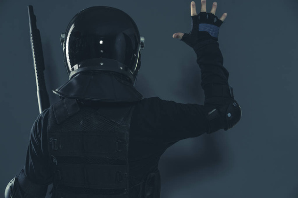 Αστυνομικός, αστυνομική ταραχών σηματοδότηση στους συναδέλφους με τα χέρια τους. ένοπλες άνθρωπο με το κράνος και αλεξίσφαιρο γιλέκο - Φωτογραφία, εικόνα